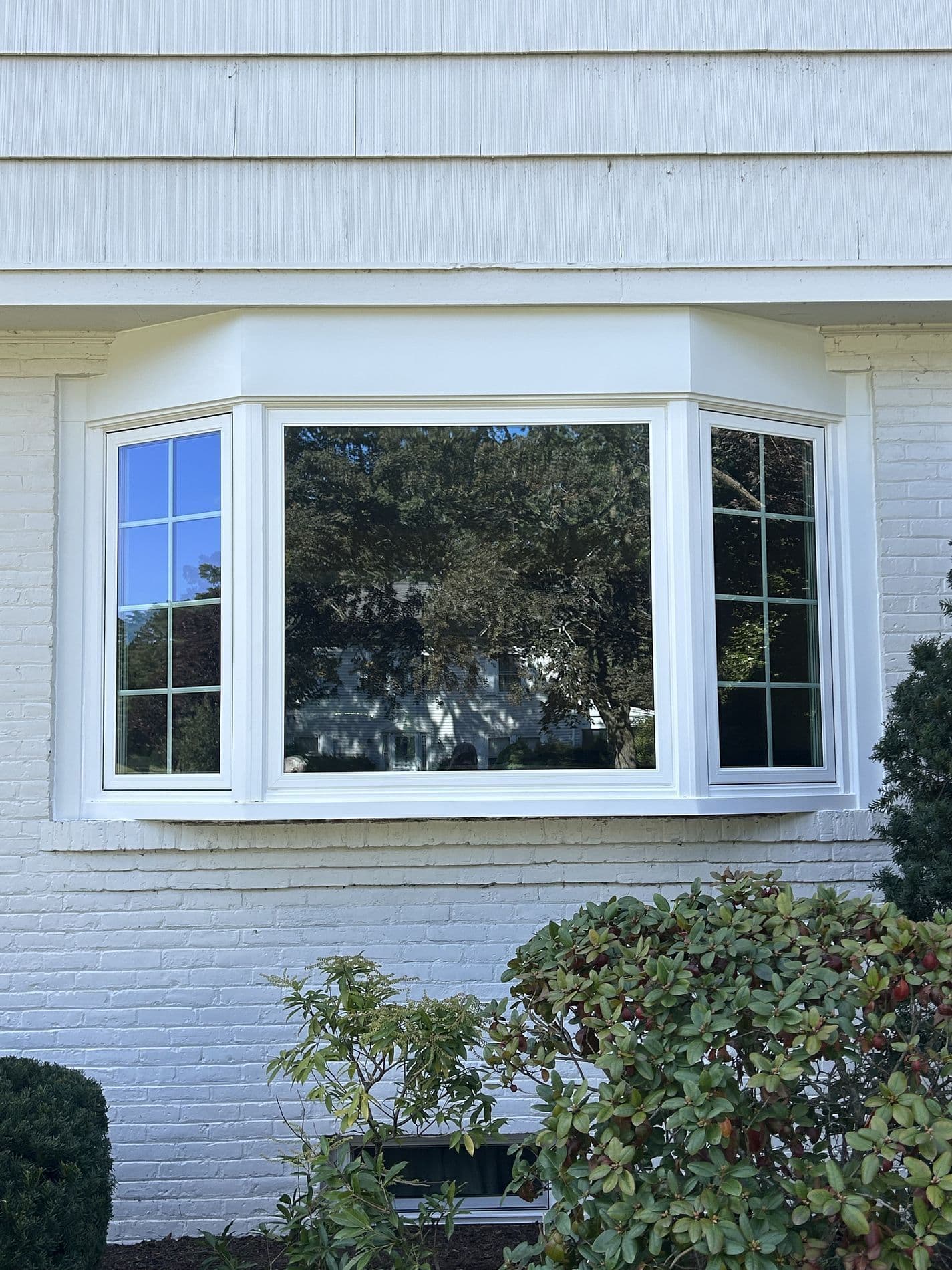 A newly-installed bay window on a white brick house.