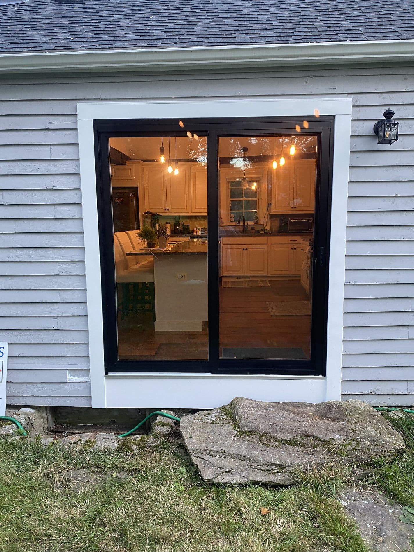 An exterior view of black sliding glass patio doors with a kitchen visible inside.