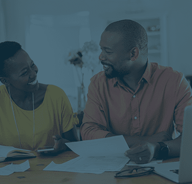 People smile at each other as they look over paperwork at a table.