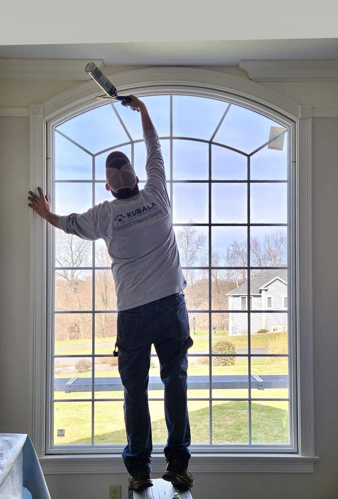 A Kubala team member works on installing a custom shaped window.