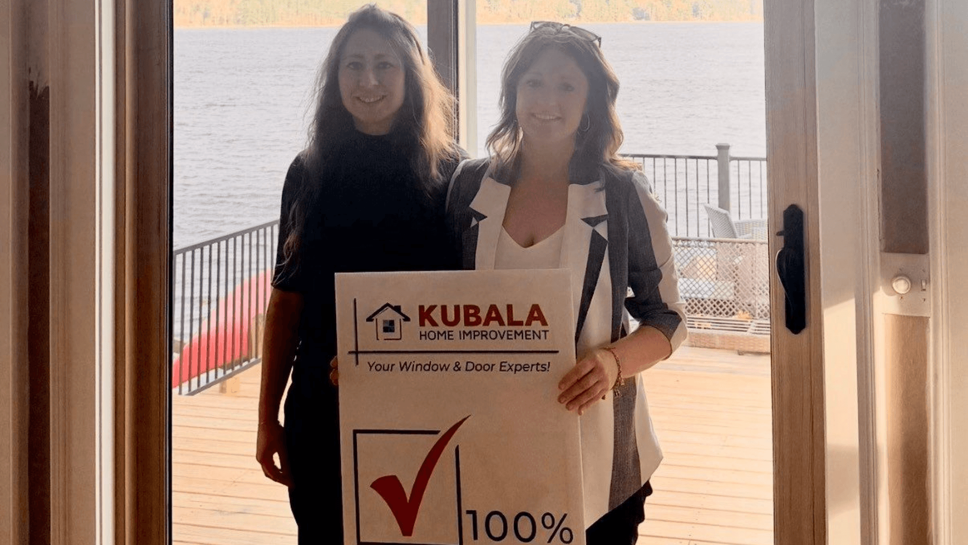 Picture of homeowners smiling and holding a "100% Satisfied" sign in front of their new windows and doors in Brookfield, MA.