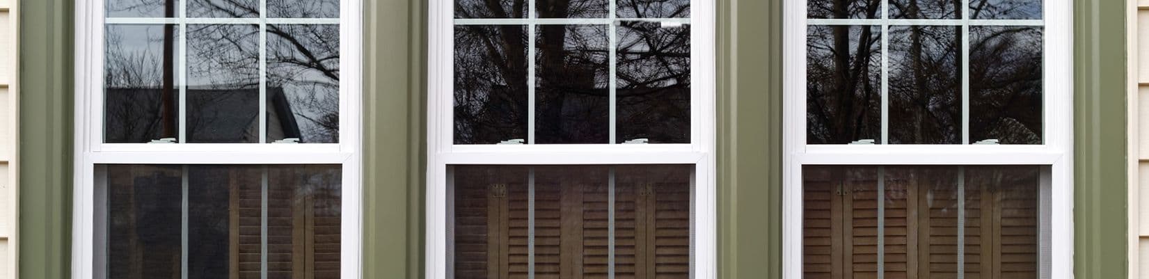 Newly-installed windows with interior brown shutters as viewed from the outside.